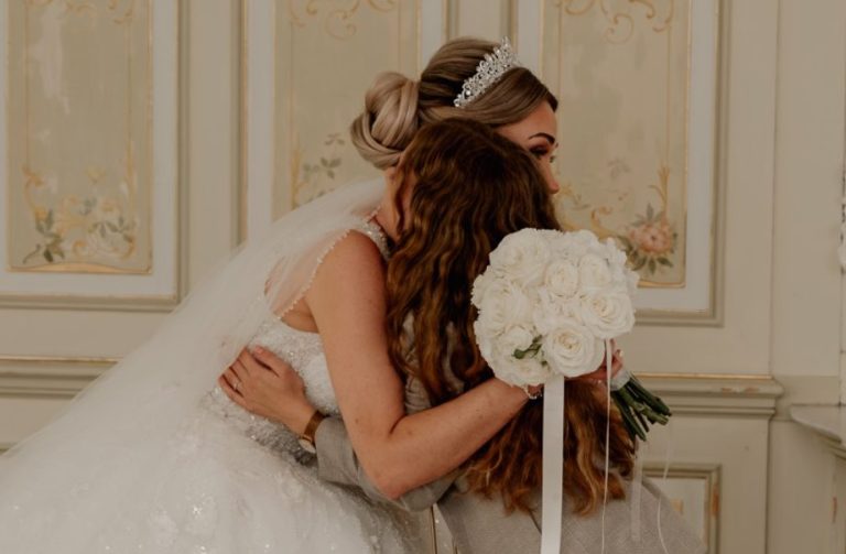 Warum mit mir? Hochzeitsplanerin Hannah in einem hellen Anzug die einen Holzstuhl auf einem Event hin und her herträgt.